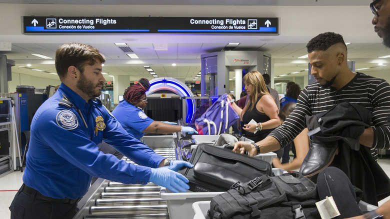 Transportation Security Administration (TSA) agents help travelers place their bags through the 3-D scanner at the Miami International Airport on May 21, 2019 in Miami, Florida.