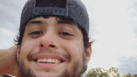 GoFundMe Julian Ryan wears a baseball cap and smiles at the camera