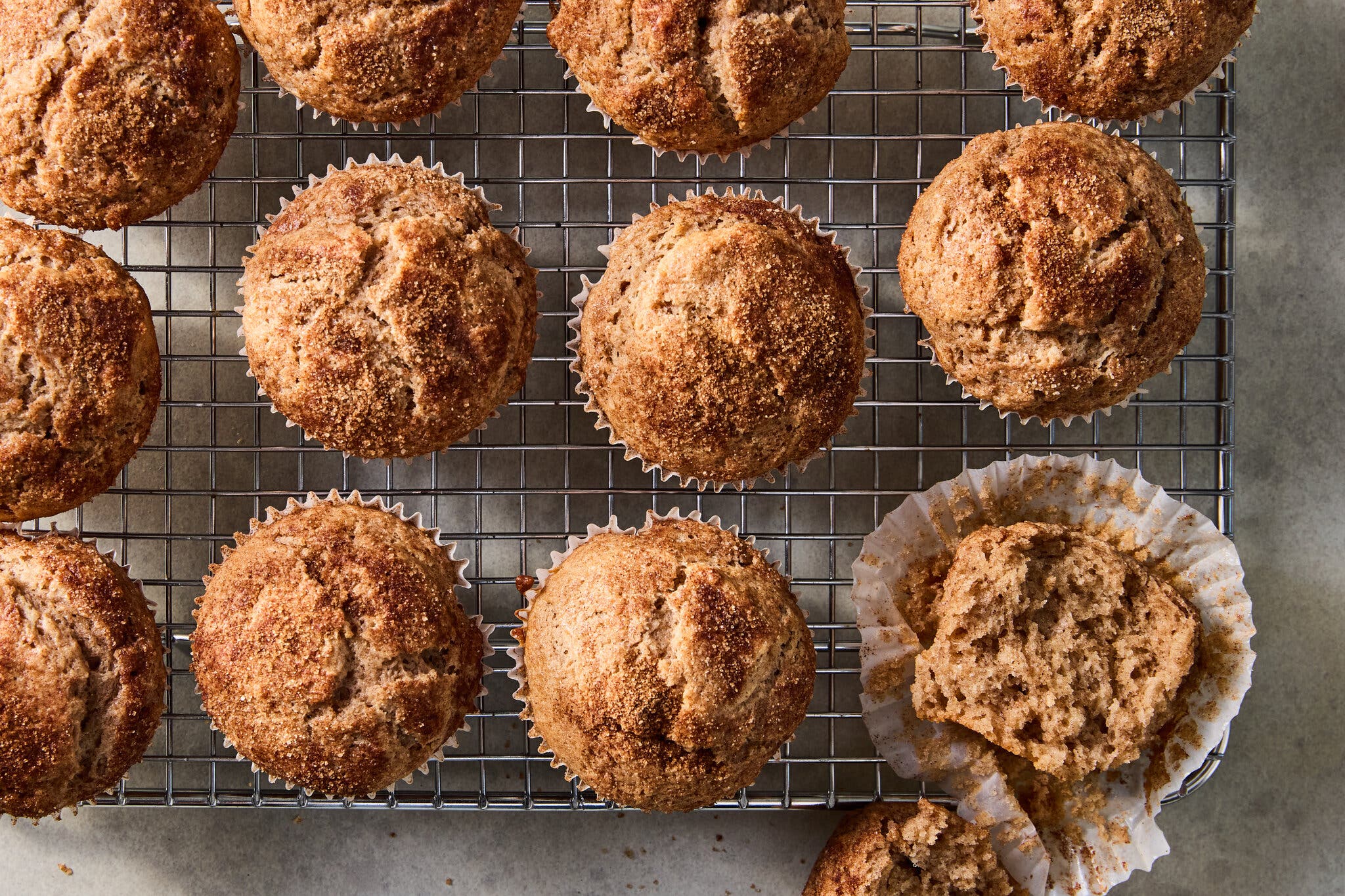 A dozen muffins coated in cinnamon sugar are photographed from overhead.