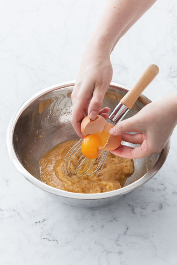 Adding eggs to sugar-butter mixture that has been slightly cooled.