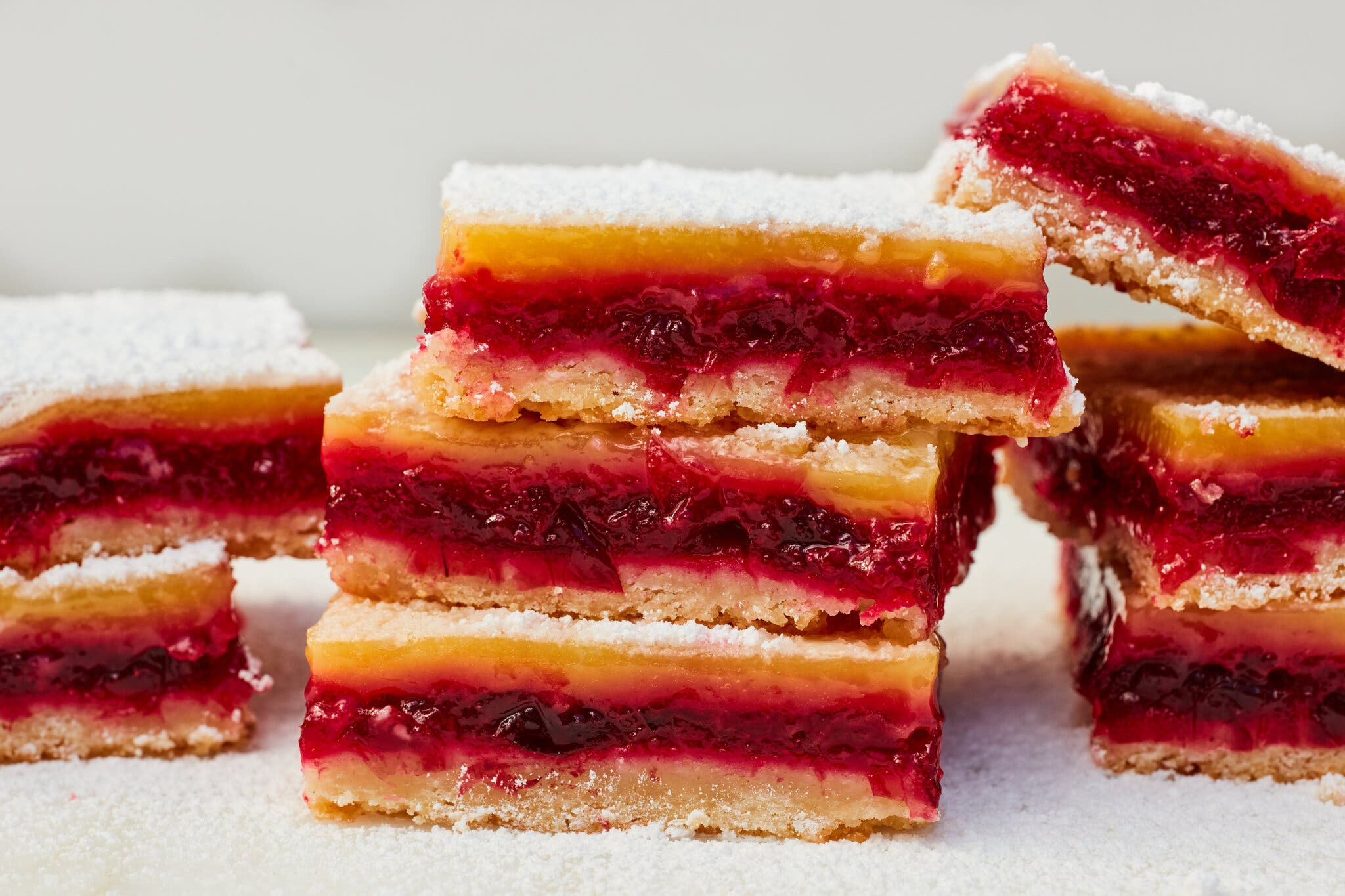 Stacks of lemon bars with a thick cranberry layer in the center.