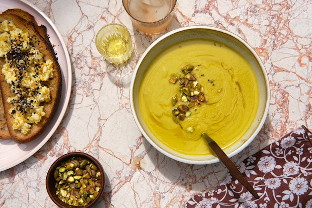 blended vegetable soup served on a pink marble table with cloth napkin and soup spoon