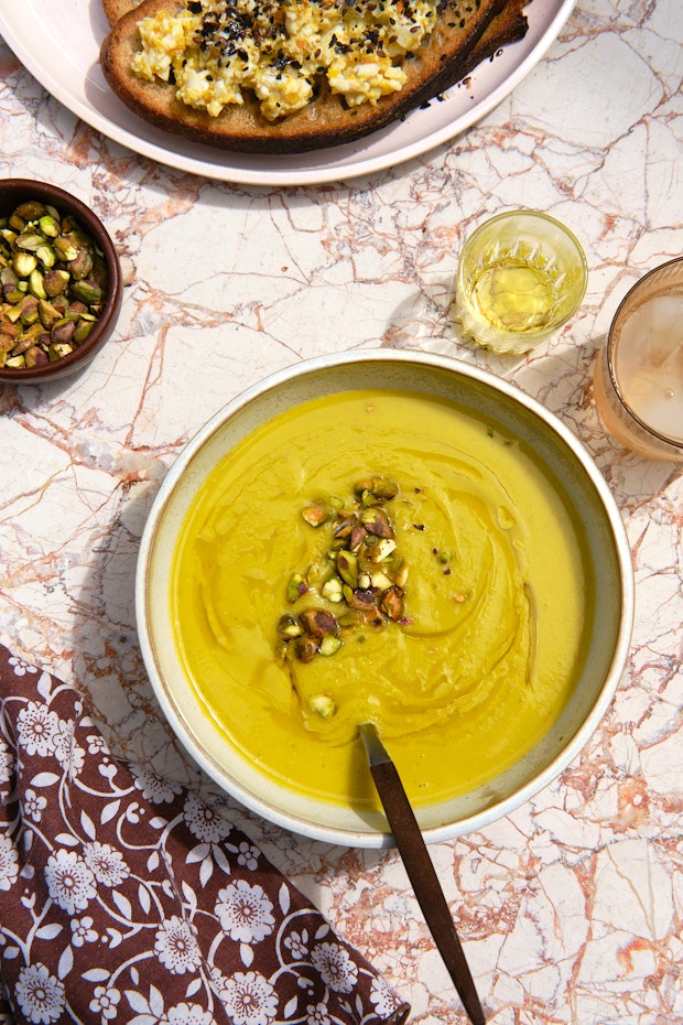 blended vegetable soup served on a pink marble table with cloth napkin and soup spoon