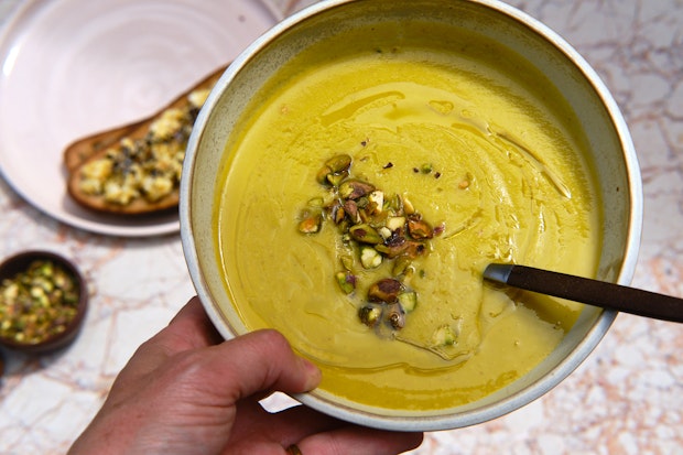 a hand holding a bowl of soup